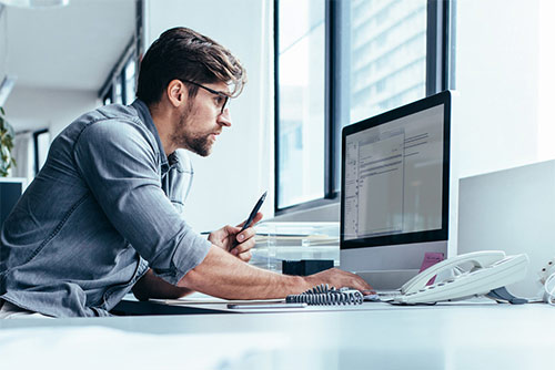 Mann, der an Computer arbeitet und Stift in Hand hält
